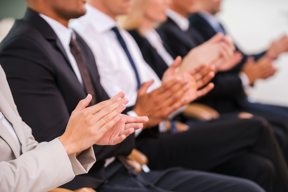 People in suits clapping at a business event
