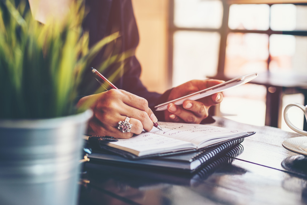 Writing notes with pen and paper at desk