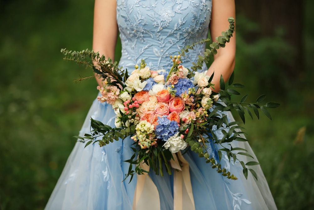 Bride in a pale blue wedding dress and holding a bouquet