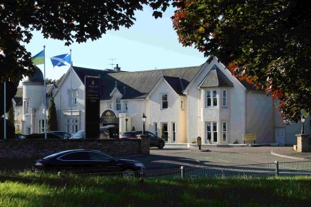 Kingsmills Hotel from neighbouring park with Autumn trees and car passing by