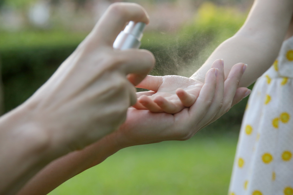 Parent putting spray on child's hands and arms