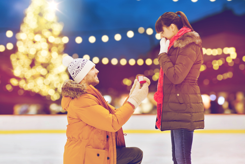 A man proposing to a woman on an ice rink at Christmas