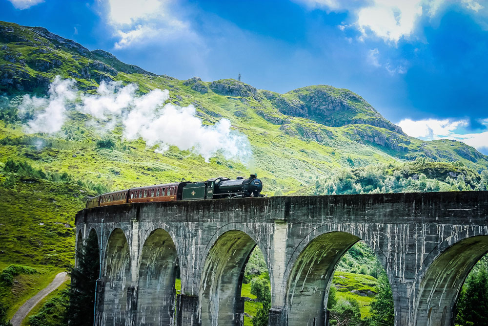 The Jacobite Steam Train travels over the Glenfinnan Viaduct in the Scottish Highlands