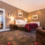 Generous living space with a bed and armchairs at Kingsmills Hotel, Inverness