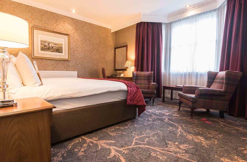 A large bed and armchairs at Kingsmills Hotel, Inverness