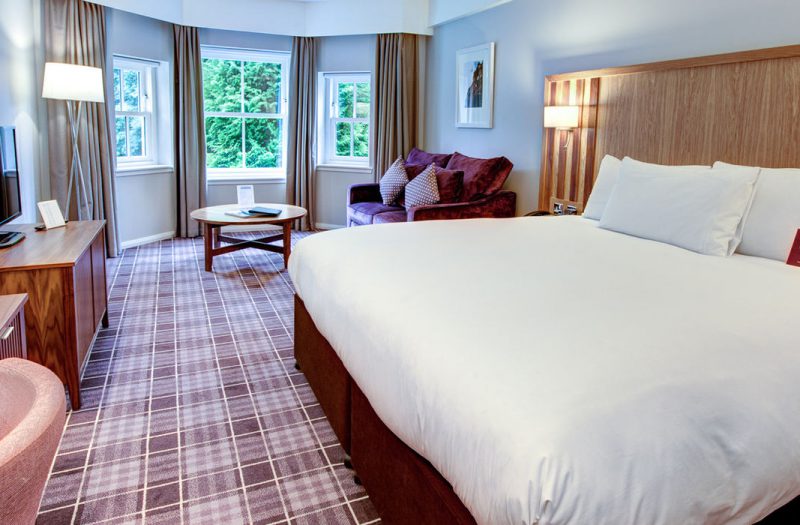 A bed and sofa in the living area at Kingsmills Hotel, Inverness