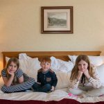 Three children sitting on a bed in a luxury family room at Kingsmills Hotel
