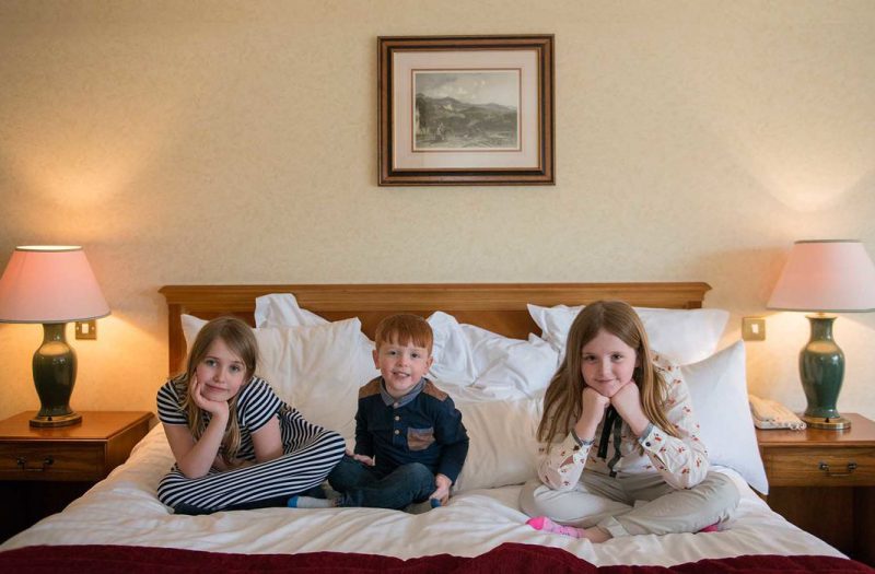 Three children sitting on a bed in a luxury family room at Kingsmills Hotel