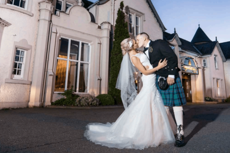 A bride and groom kissing in front of the Kingsmills Hotel