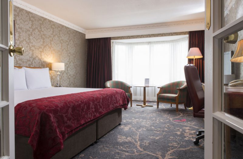 A large bed with bright, big windows at Kingsmills Hotel, Inverness