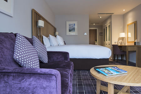 A double bed and sofa in a luxury room at Kingsmills Hotel