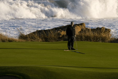 Golfer playing on a green by the sea