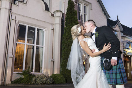 A bride and groom kissing outside the Kingsmills Hotel