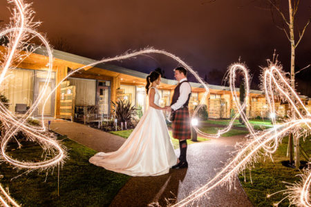 A bride and groom with sparklers swirling around them
