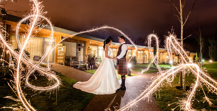 A bride and groom with sparklers swirling around them