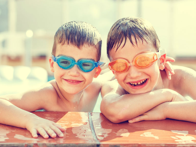 Two boys having fun with goggles on in a swimming pool
