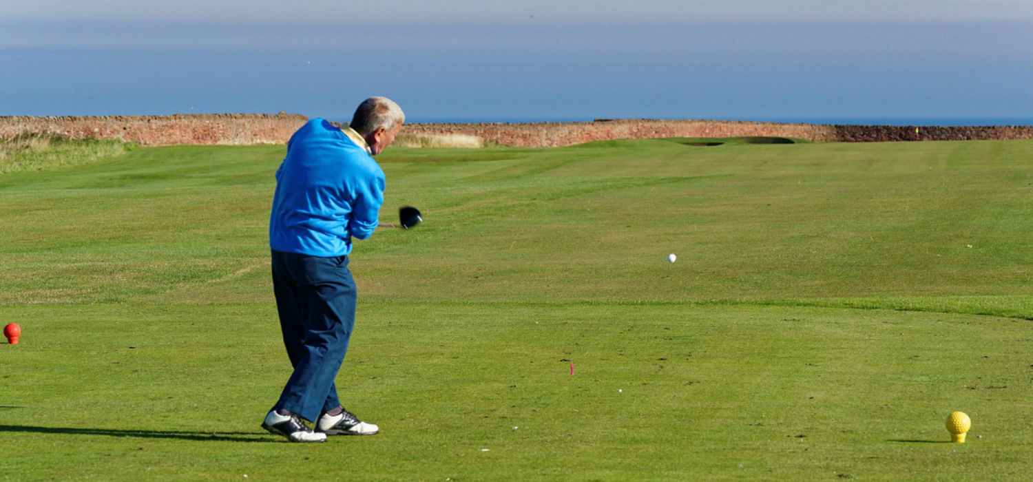 A man playing golf by the sea.