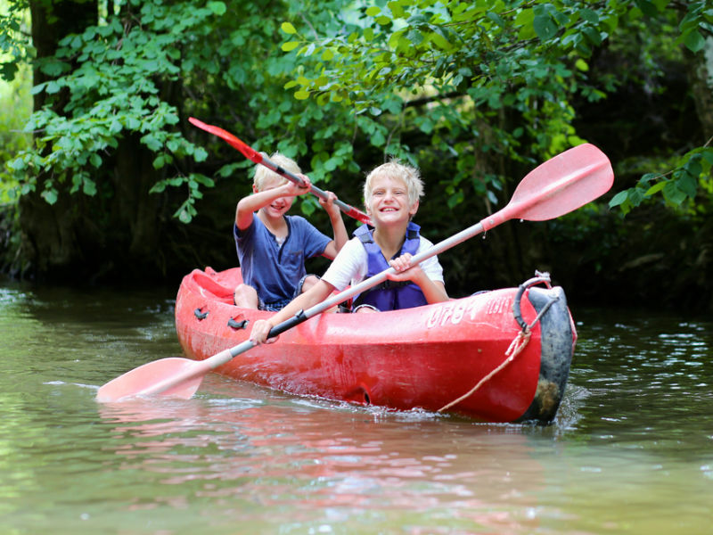 Two young boys enjoying a canoe on a river.