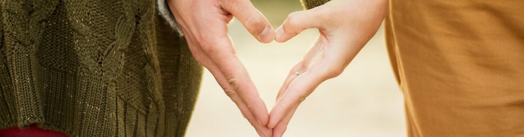 Couple making a love heart with their hands