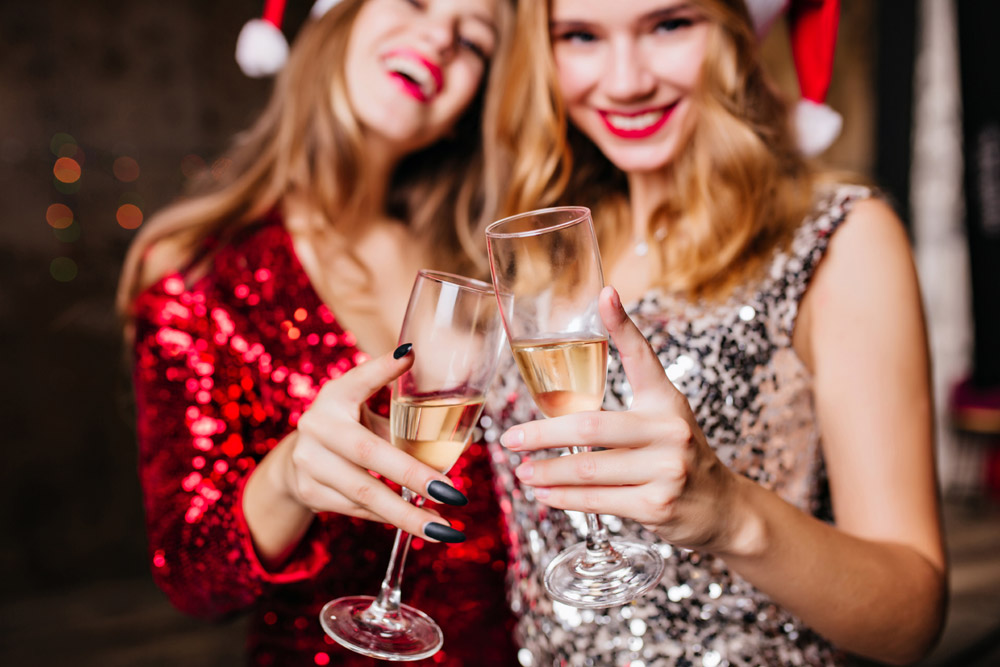 Two women in Santa hats with champagne