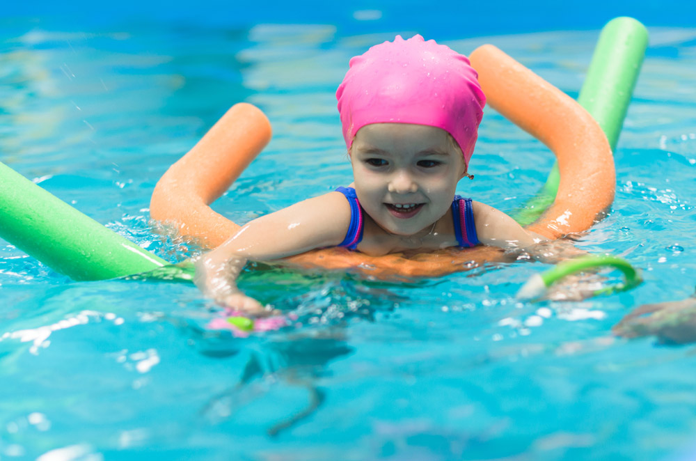 Child learning to swim with colourful floats