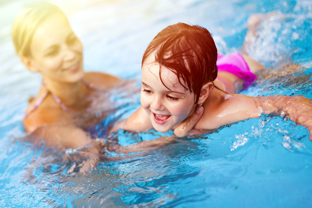 Mother and daughter swimming in pool