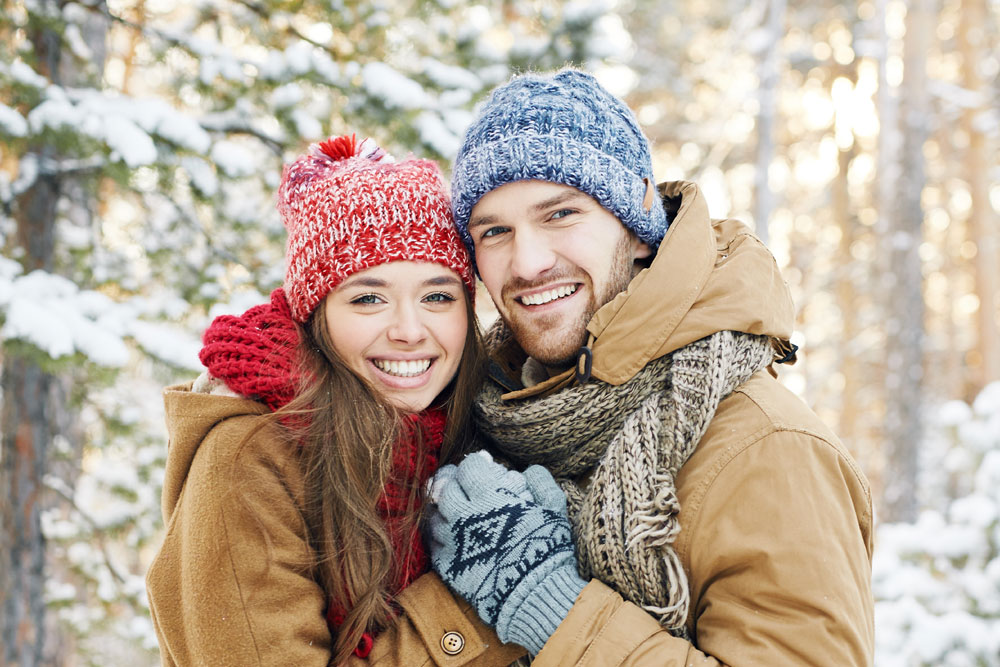 Happy couple in the snow surrounded by forest
