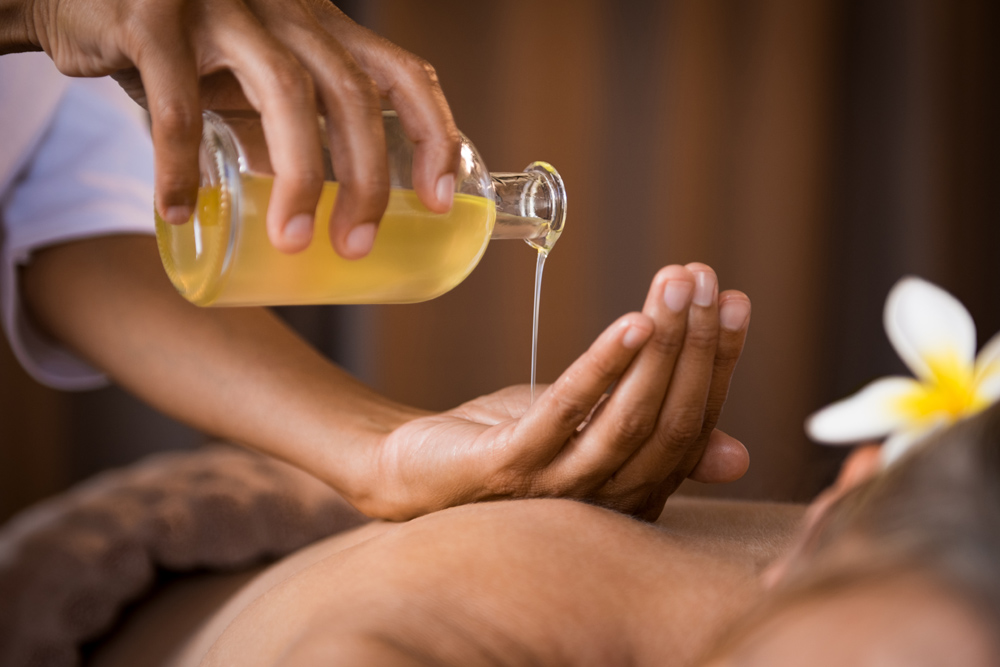 Therapist pouring essential oils onto hand for massage
