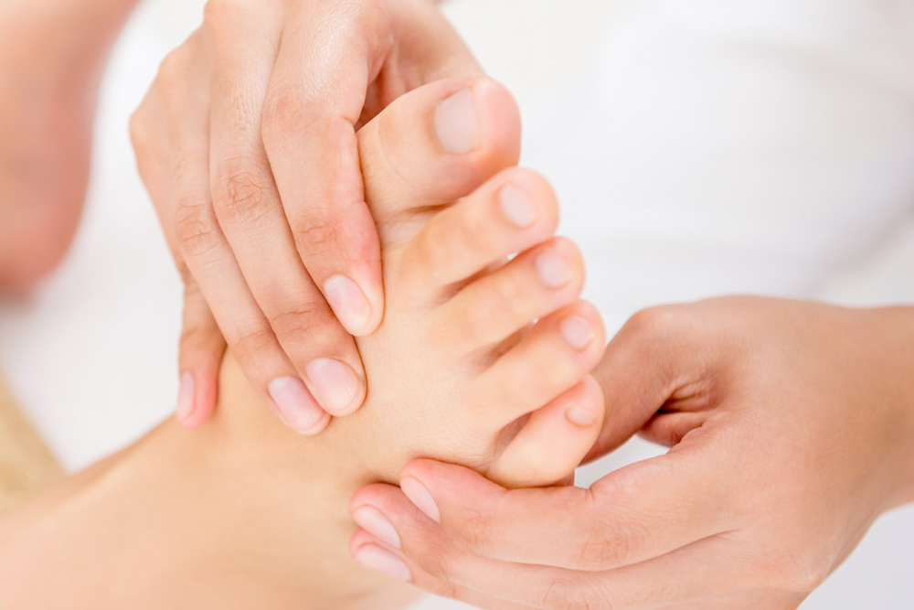Close up of person receiving reflexology treatment on feet