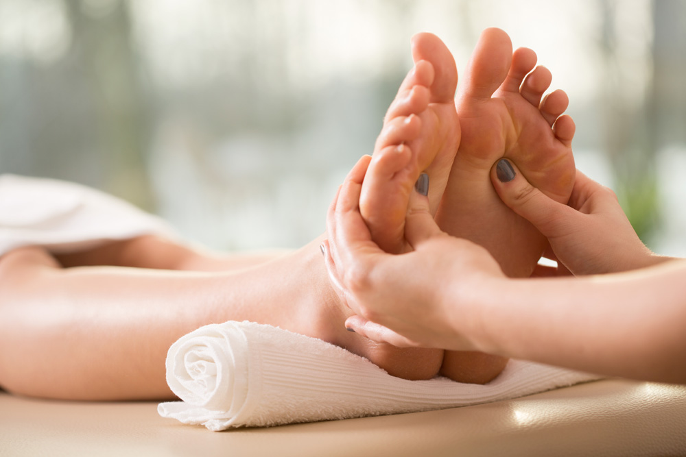 Close up of person receiving reflexology treatment on feet