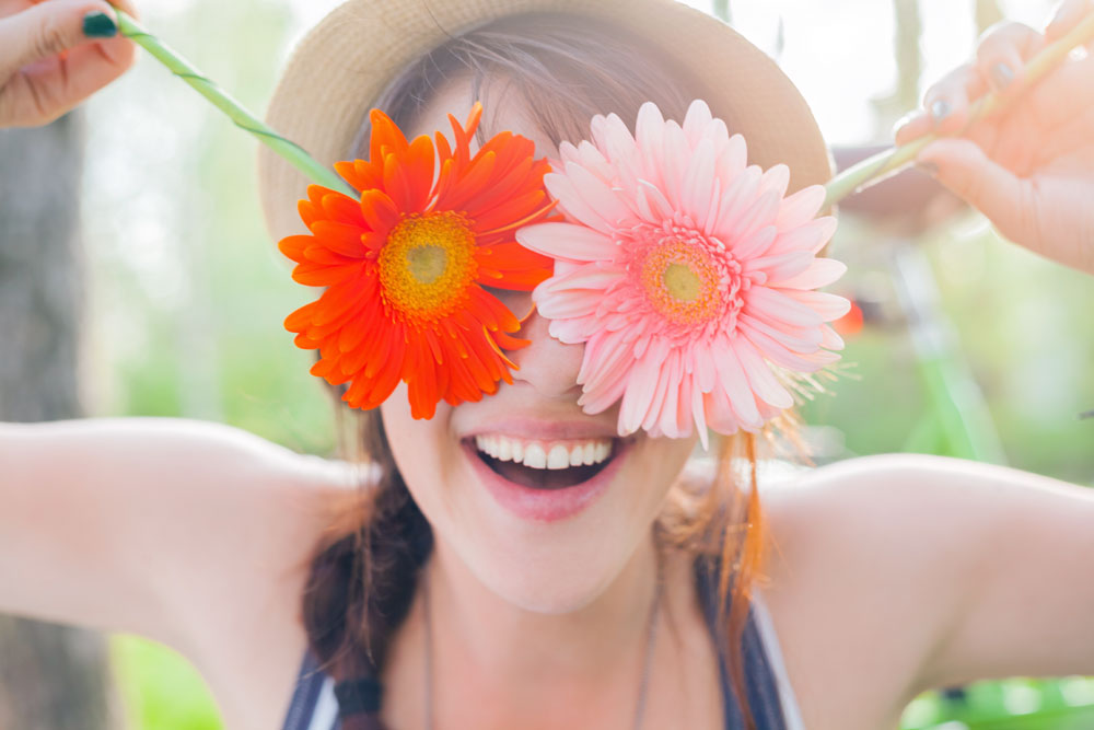 Smiling woman holding spring flowers over her eyes