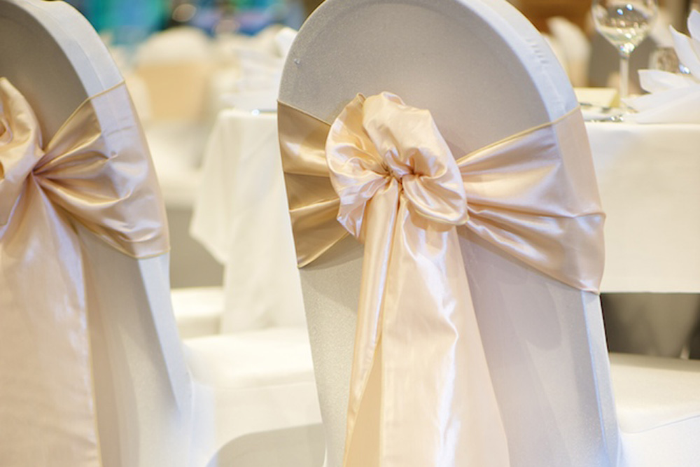 Chairs with white covers and peach ties