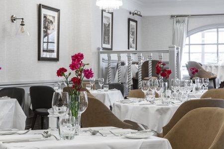 Restaurant set for dinner service with white table cloths and tan chairs