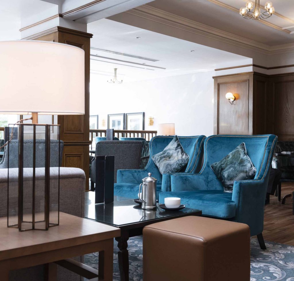 Two blue armchairs and a large lamp in the bar and lounge at Kingsmills Hotel