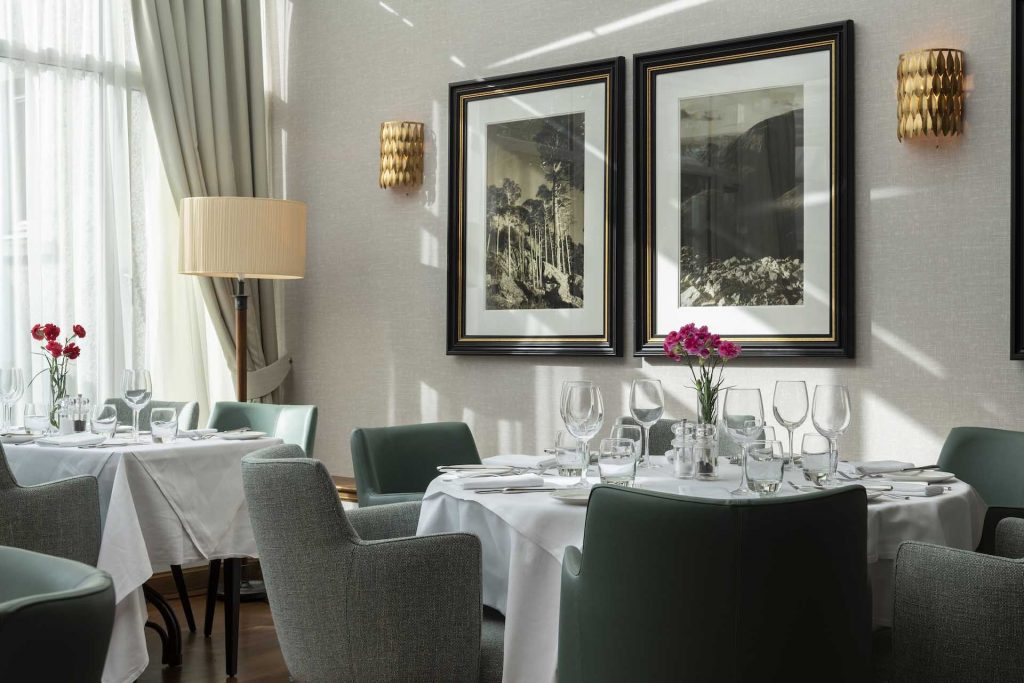 Tables set for dining by a window in the conservatory restaurant at Kingmills Hotel