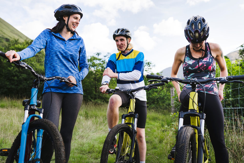 Three people with bikes in the countryside