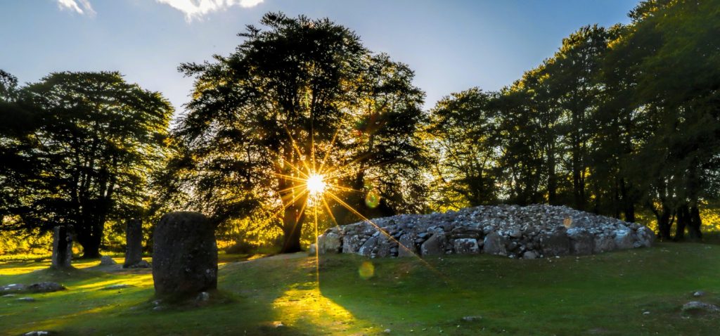 Sunshine poking through the trees as the sky darkens at Clava Cairns burial site