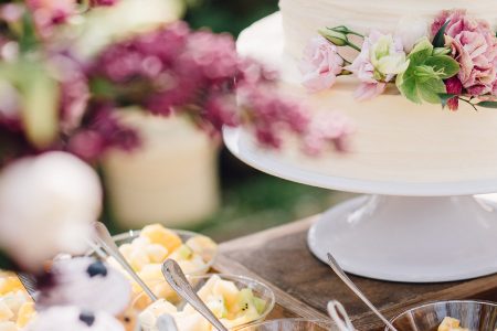 Wedding cake, flowers and food laid out on table