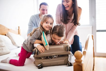 A family trying to close a suitcase after packing
