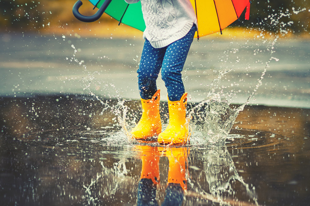 Child in yellow wellies splashing in a puddle
