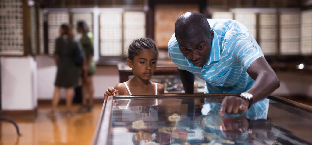 A man shows an item in a museum display to a child
