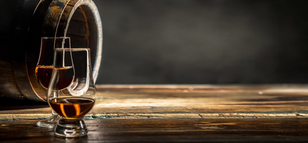 Glasses of whisky sit in front of a cask