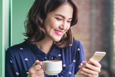 Woman with a coffee using a phone app