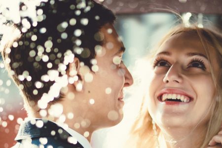 Bride and groom standing in the rain under an umbrella