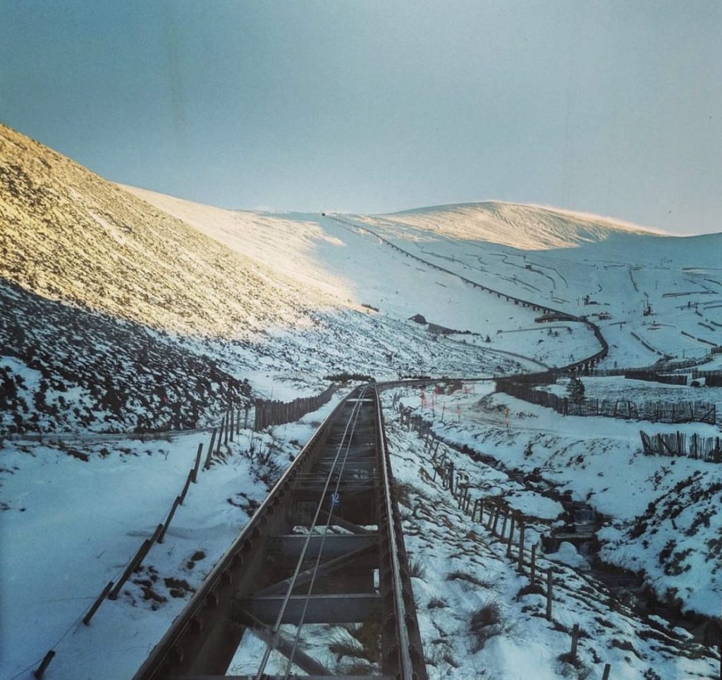 Cairngorm funicular railway heading up the Cairngorm Mountains with clear train lines and snow