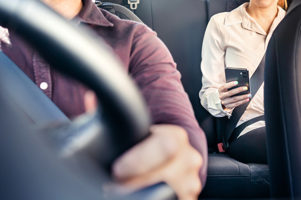 Woman with phone sat in the back of a taxi