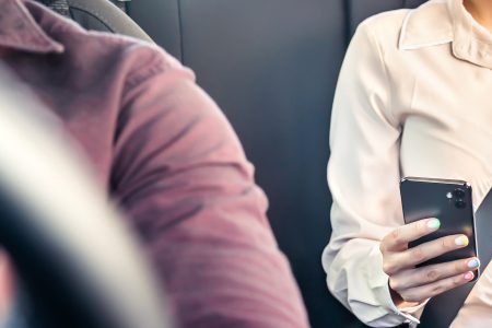 Woman with phone sat in the back of a taxi