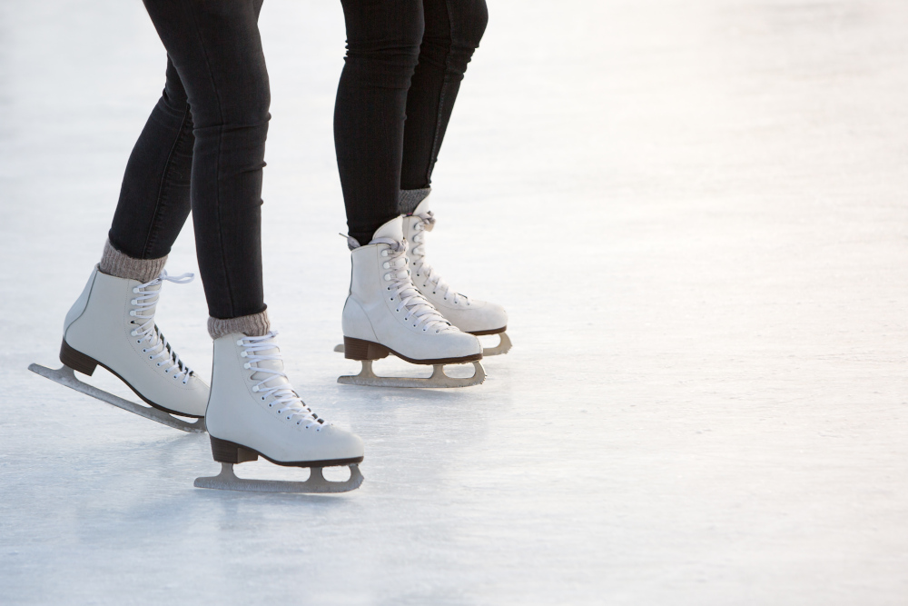 Close up of two people's skates on the ice rink