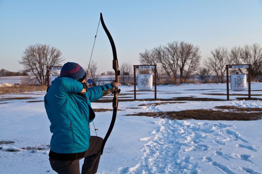Man aiming his recurve bow at the outdoor archery range.