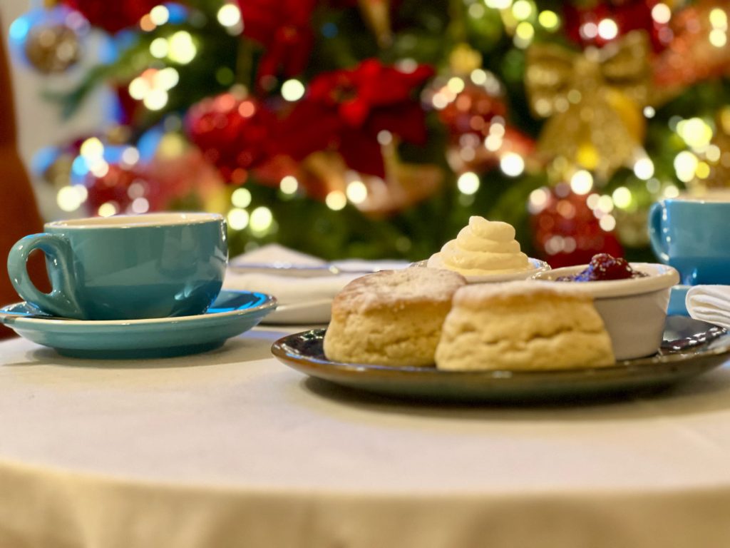 Scone, jam and cream with christmas tea in background.